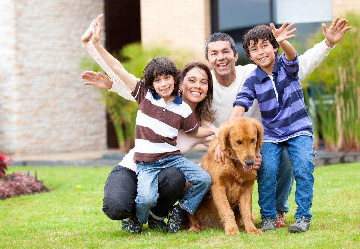 A smiling family outdoors with their golden retriever